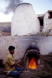 Image du Maroc Professionnelle de  Sur la Colline des Potiers un ouvrier utilise le genêt pour chauffer le four de cuisson des poteries en céramique à Safi, Vendredi 29 Août 1997. (Photo / Abdeljalil Bounhar)